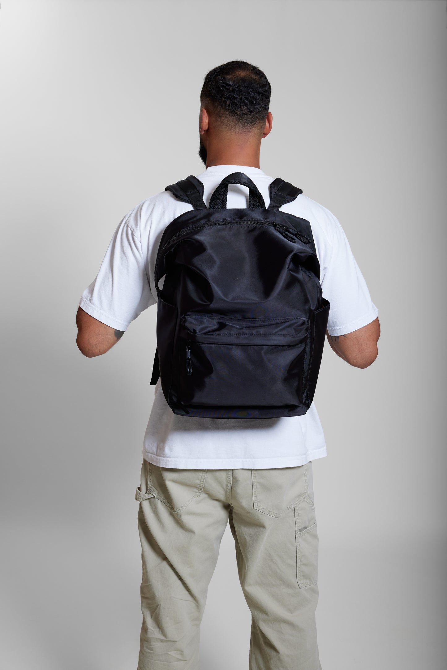 Male model wearing Karma Black Backpack