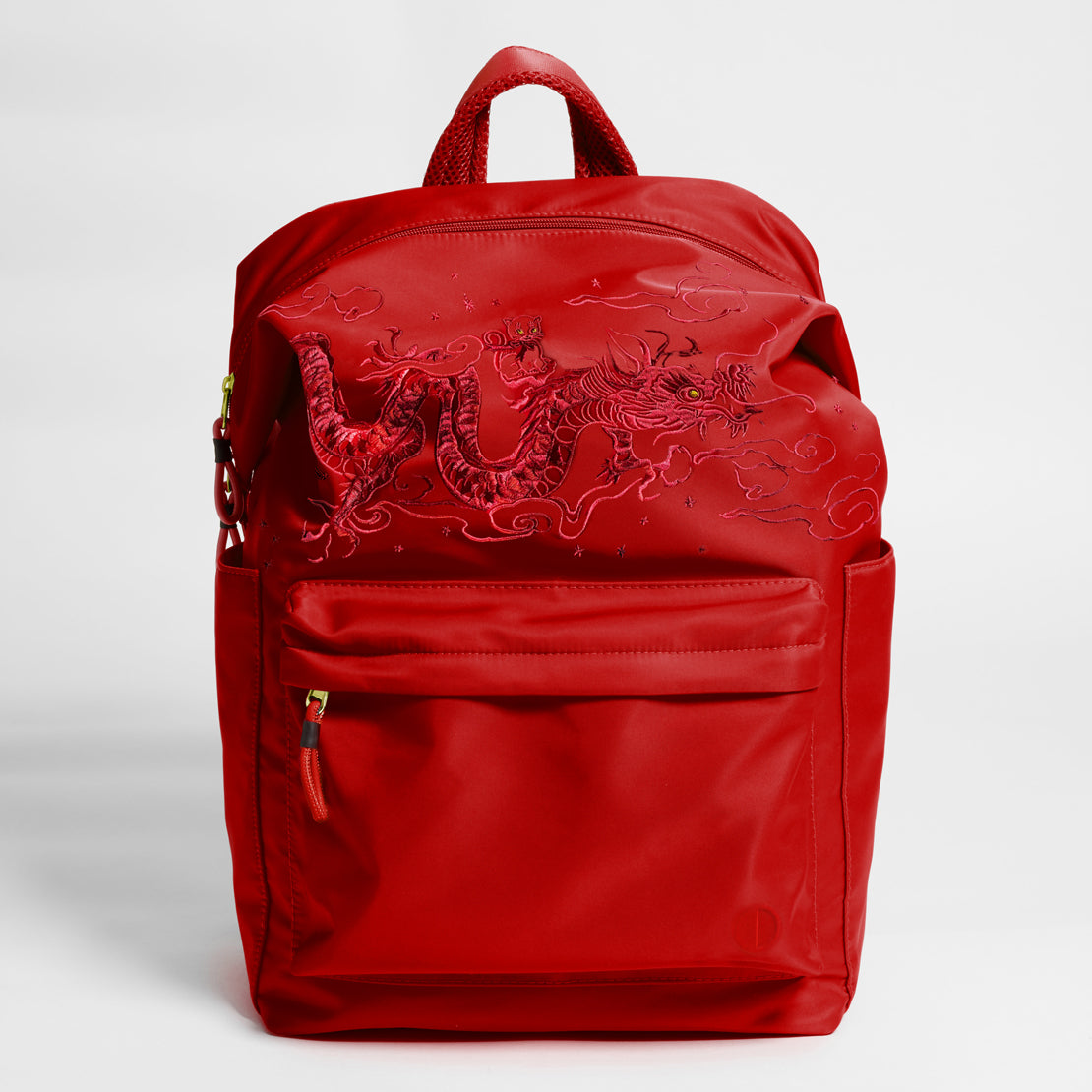 Front Facing view of the Karma Backpack in Red Nylon with intricate dragon embroidery. Backpack has a top handle and a convertible strap to carry your backpack as a tote for easy grab and go!
